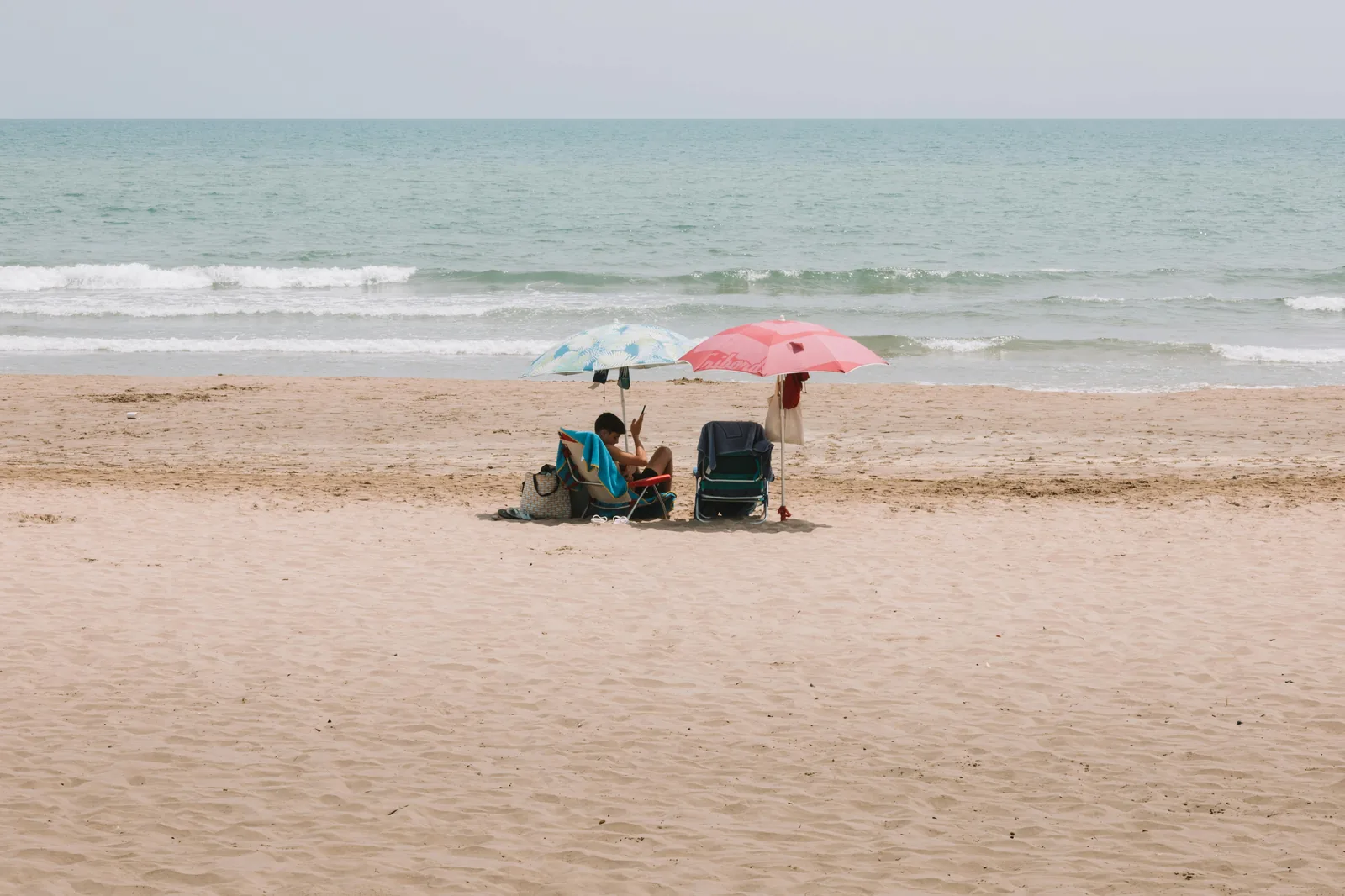 Bébé sous un parasol sur une plage calme : voyager à Majorque avec un nourrisson.