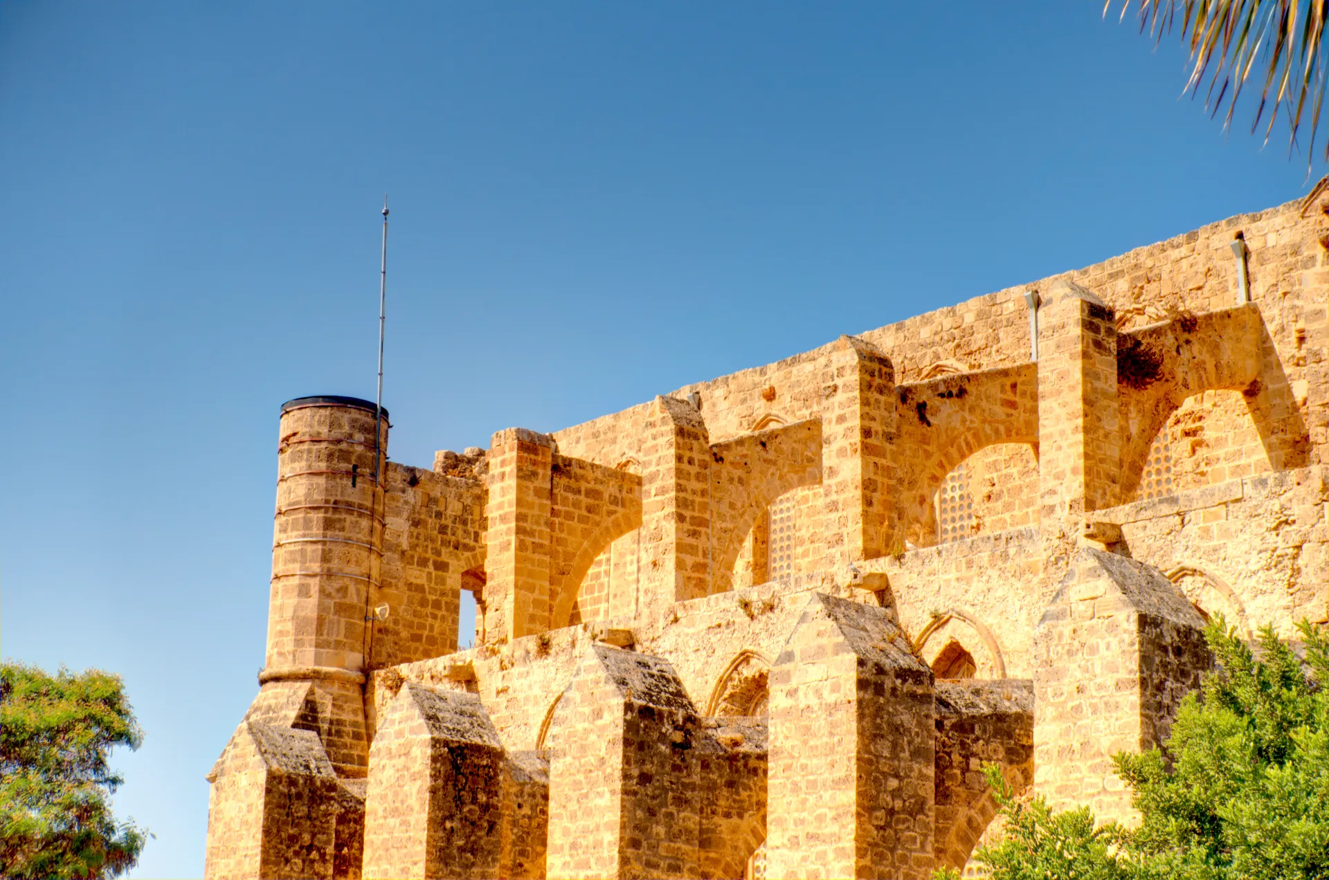 Ruines d'une ancienne structure en pierre de couleur ocre sous un ciel bleu clair, avec des arches et des murs épais