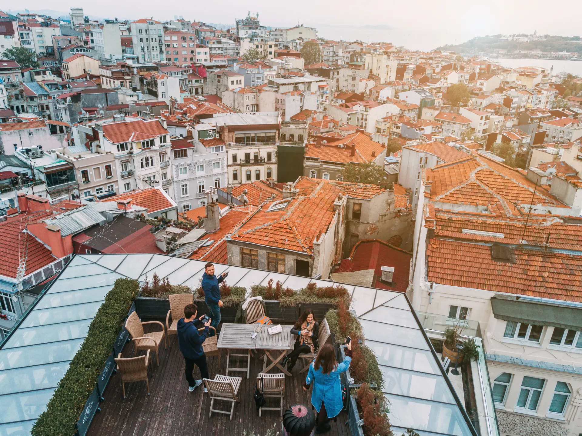 Vue aérienne d'un toit-terrasse avec des personnes profitant de la vue sur une ville méditerranéenne aux toits rouges