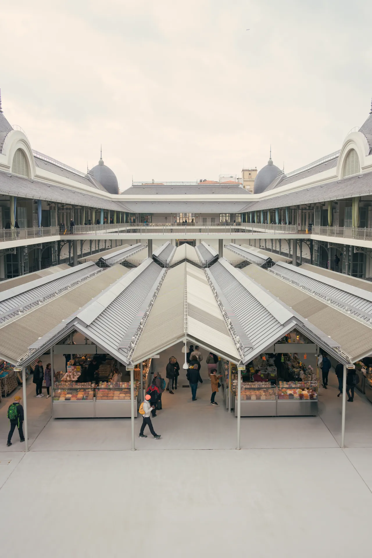 Vue aérienne d'un marché couvert avec des étals de nourriture et des personnes se promenant sous un grand bâtiment architectural