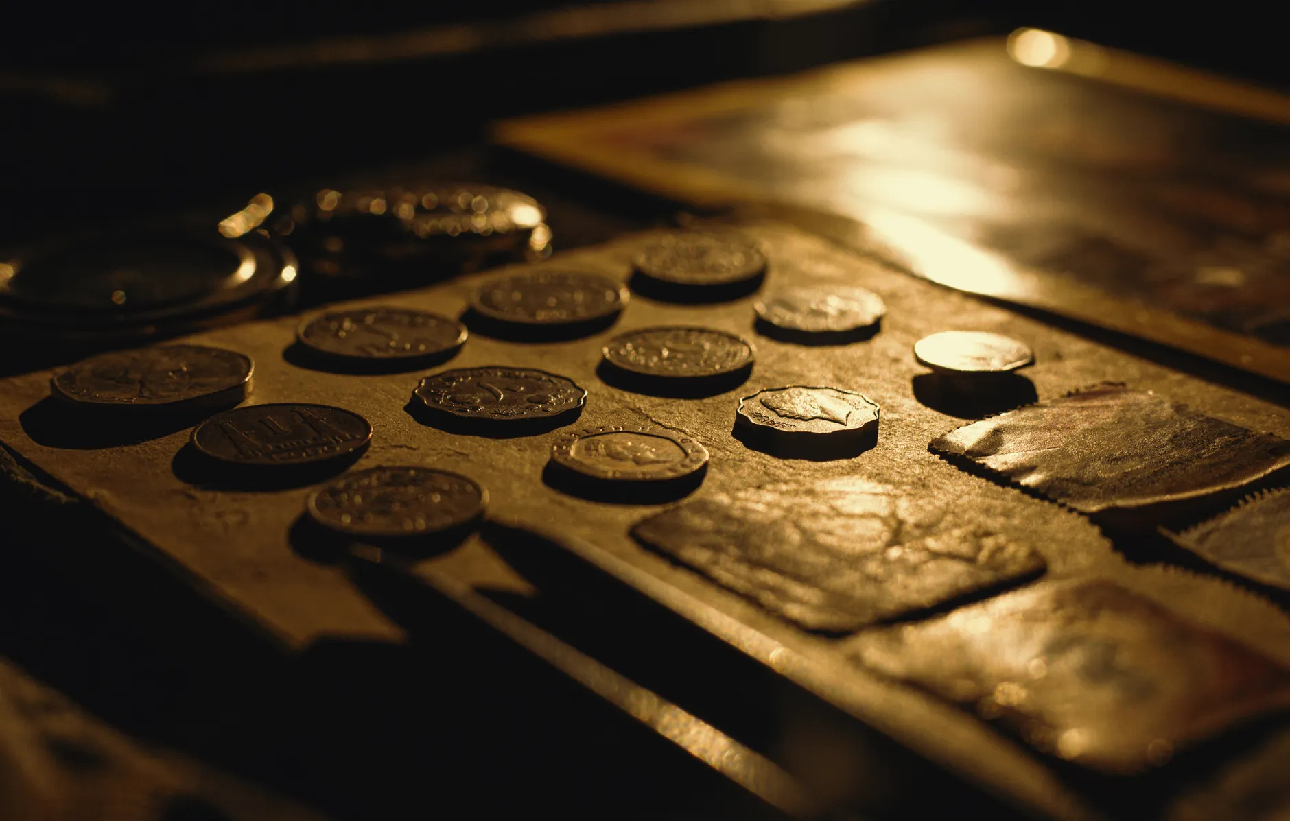 Close-up of antique coins on a table, captured with dramatic lighting and rich textures.