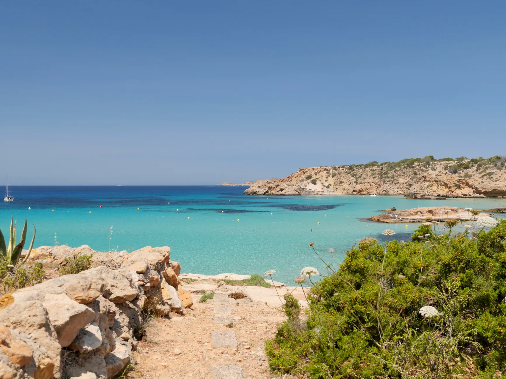 Beautiful view of Cala Tarida beach in Ibiza with turquoise waters and clear blue sky.